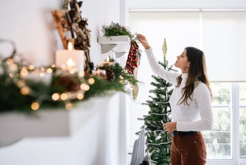 Young Woman at Home Putting Up Holiday Decorations