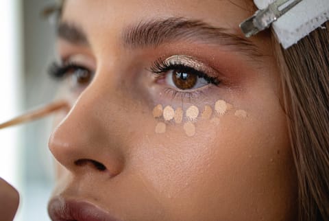 Woman with dots of concealer ready to blend under her eyes