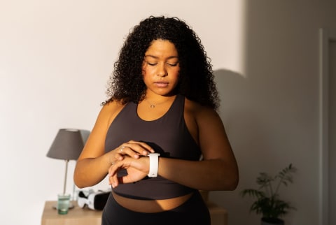 Woman Looking At Smart Watch In Sportswear At Home