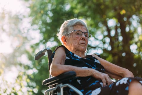 Elderly woman with osteoporosis-related hip fracture sits in wheelchair
