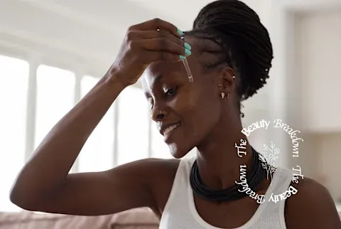 a black woman applies serum to her face using a dropper