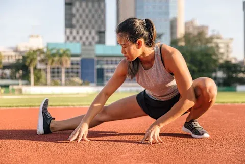 Woman Stretching Before a Run on a Track Woman Stretching Before a Run on a Track