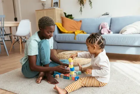 black mother playing with her young daughter using blocks