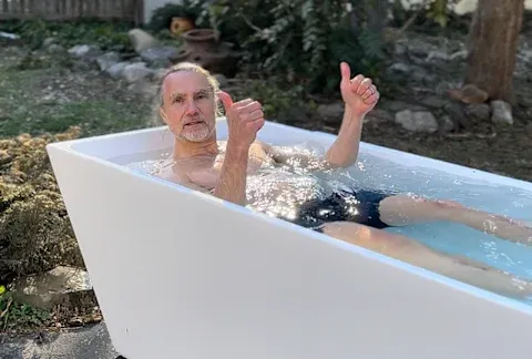 Tester sitting in the plunge cold plunge tub with thumbs up in his home garden 