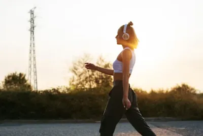 Woman walking on road at sunset wearing headphones