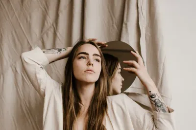 Image of a woman holding mirror to her face, showing signs of a somatic narcissist.