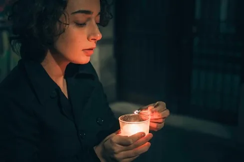 Woman Lighting A Candle In The Darkness Woman Lighting A Candle In The Darkness
