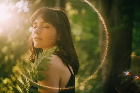 Portrait Of Young Woman With Eyes Closed And Fern In Her Hands. Standing In The Forest Catching Sun Rays Portrait Of Young Woman With Eyes Closed And Fern In Her Hands. Standing In The Forest Catching Sun Rays