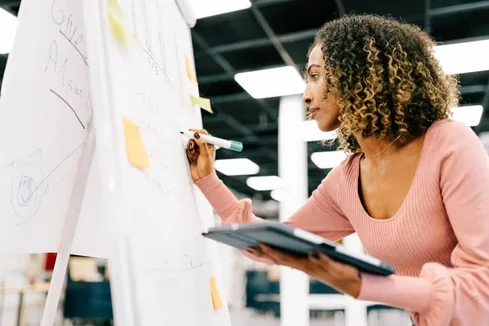 Young business woman writing ideas in a white board in a modern office Young business woman writing ideas in a white board in a modern office